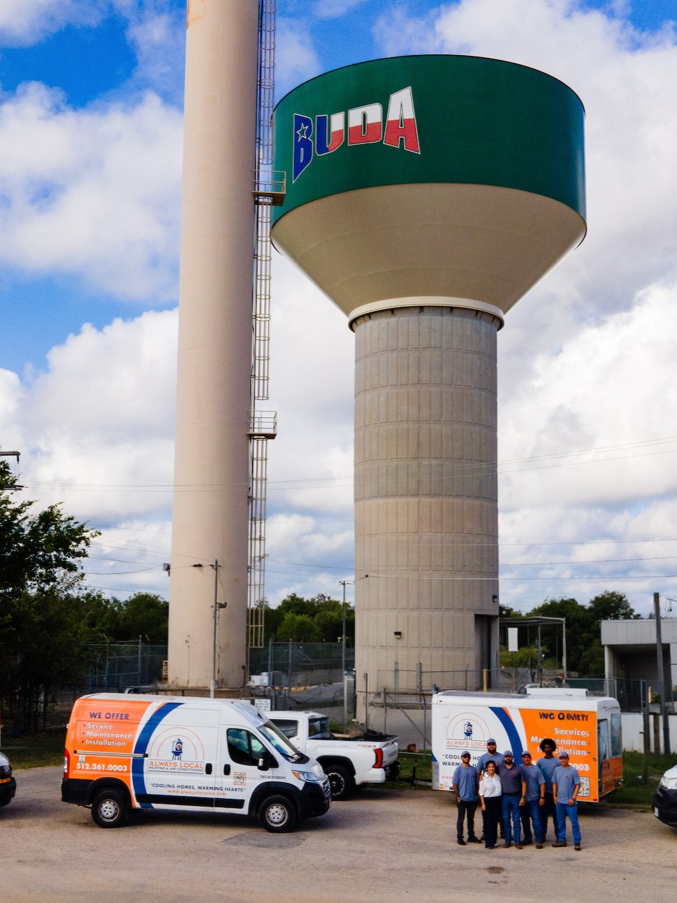 The Always Local crew and their branded vans in front of the Buda water tower