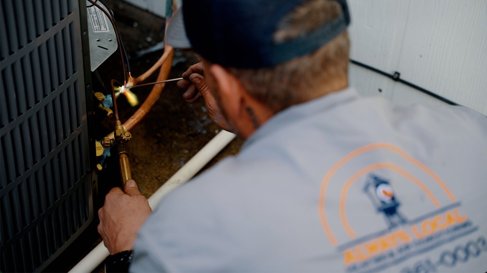 An Always Local technician checking refrigerant pressure at an outdoor condenser