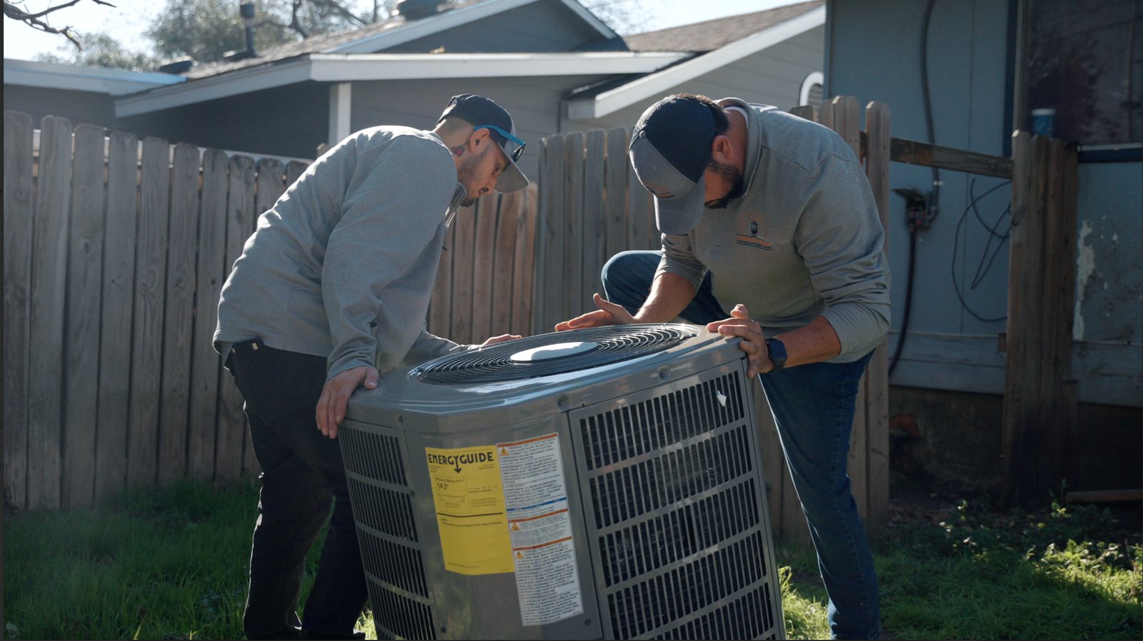Two Always Local technicians setting a new outdoor condenser unit